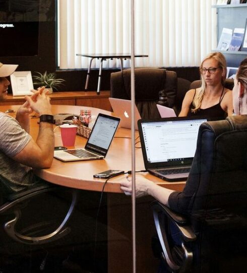 A small team meeting around a conference table with laptops open